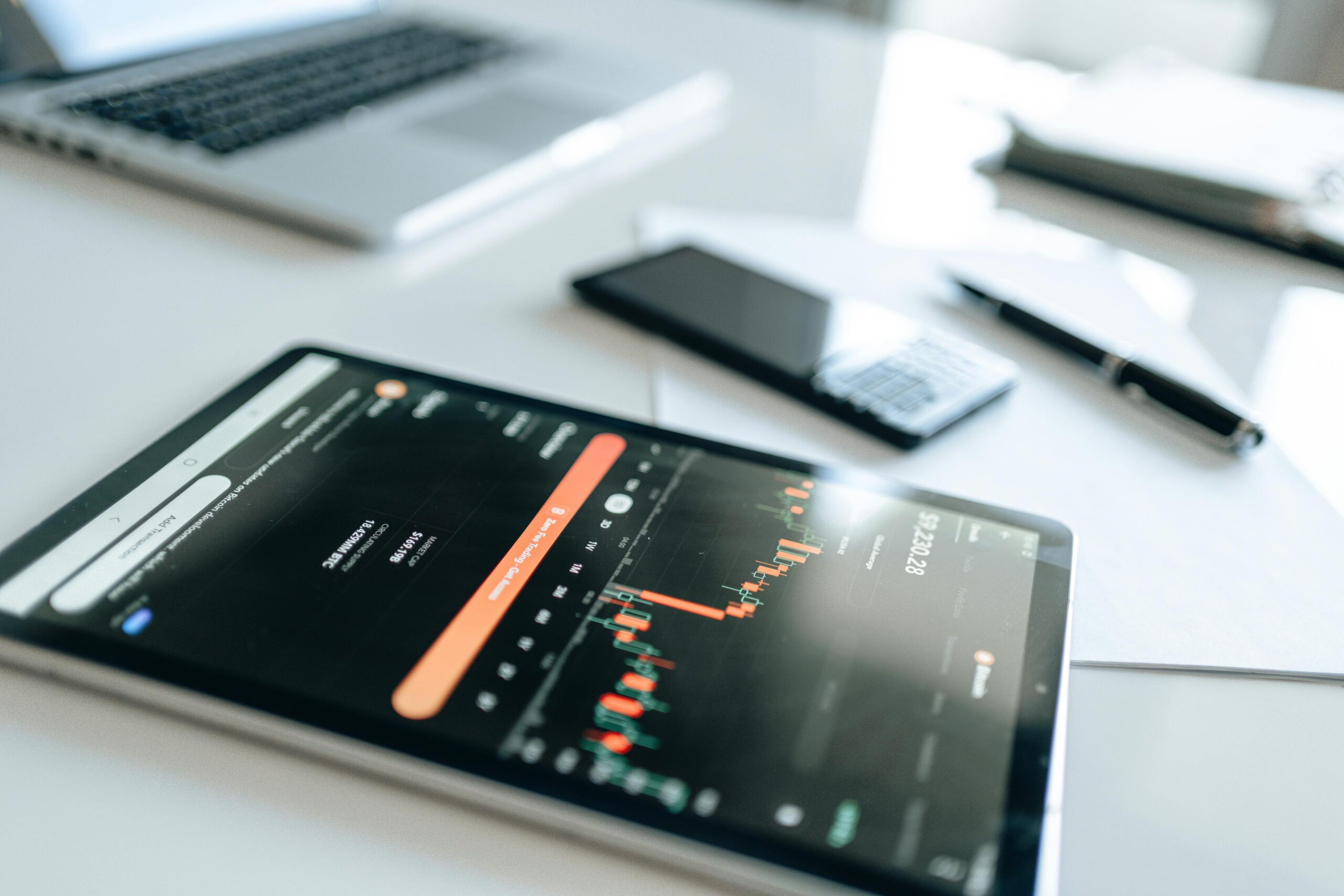 Modern financial tools including tablet with market trends on white desk setup.